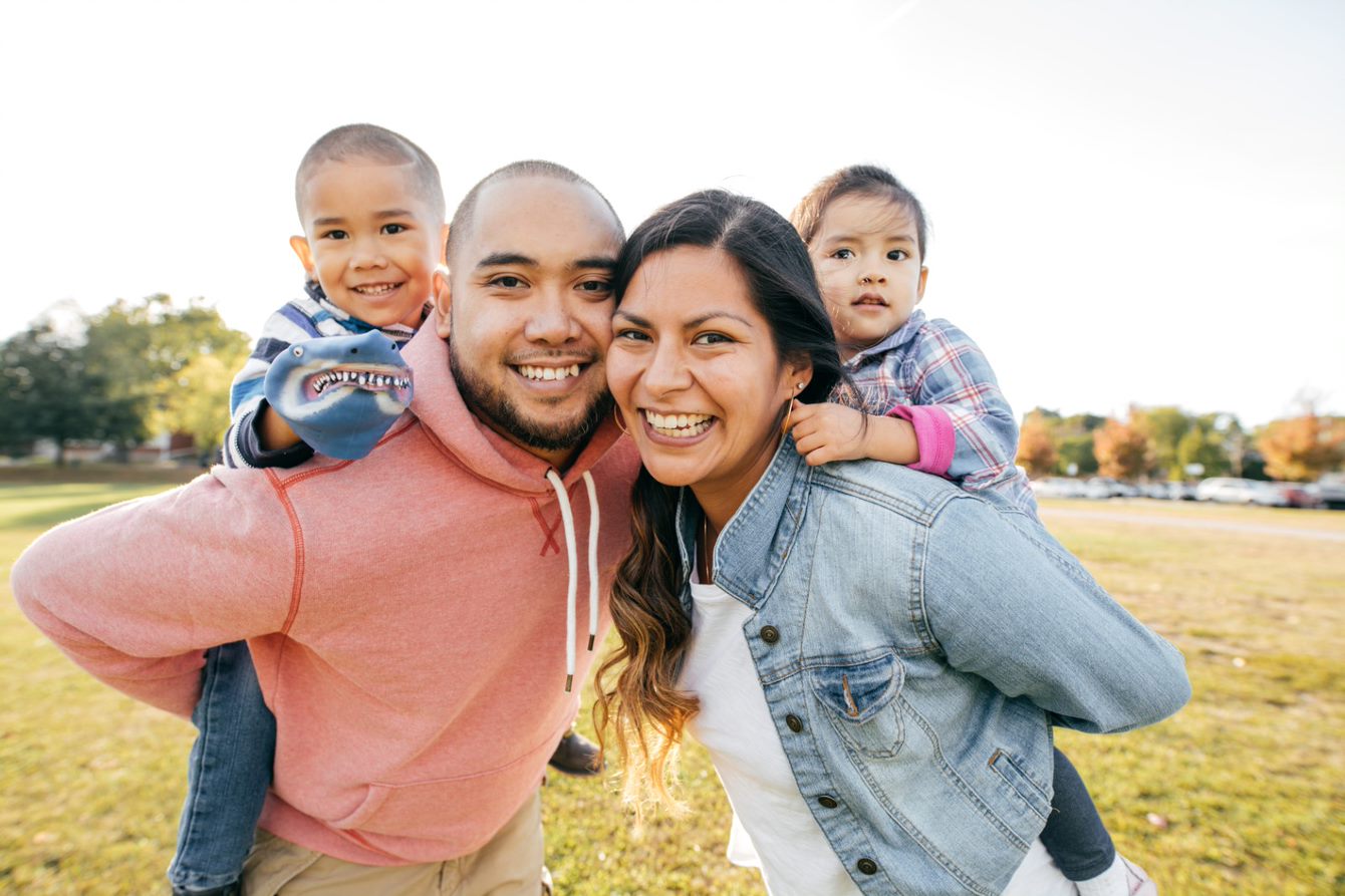 A man and woman piggy back their small children outside